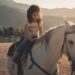 woman in white shirt riding white horse during daytime