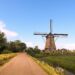 brown windmill on green grass field under blue sky during daytime